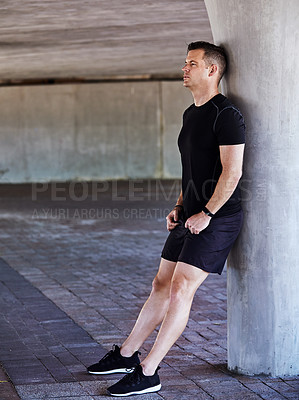 Buy stock photo Full length shot of a handsome young male athlete resting while working out in the city