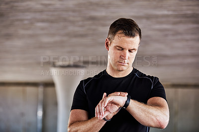 Buy stock photo Cropped shot of a handsome young male athlete checking his watch while working out in the city