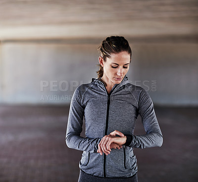 Buy stock photo Cropped shot of an attractive young female athlete checking her watch while working out in the city