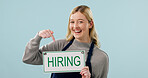 Pointing, woman and hiring sign for cafe in studio, recruitment announcement and space. Happy barista, portrait or board with onboarding info, job vacancy or work opportunity on blue background