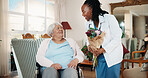 Doctor, flowers and old woman in wheelchair in home for healthcare recovery, rehabilitation and laugh. Bouquet, medical worker and person with disability, gift and homecare visit in retirement
