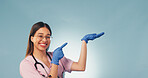 Space, portrait and nurse in studio pointing for health news, announcement and medical service. Mockup, happy and woman with gesture for healthcare, wellness tips and clinic info on blue background