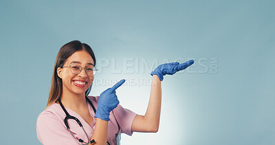 Buy stock photo Space, portrait and nurse in studio pointing for health news, announcement and medical service. Mockup, happy and woman with palm for healthcare, wellness tips and clinic info on blue background