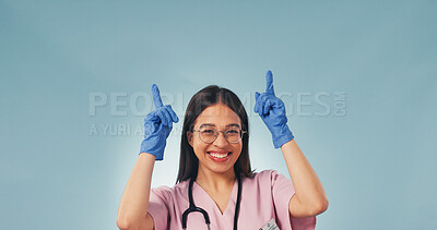 Buy stock photo Space, pointing up and portrait of nurse in studio for health news, announcement and medical service. Mockup, happy and woman with gesture for healthcare, wellness tips and info on blue background