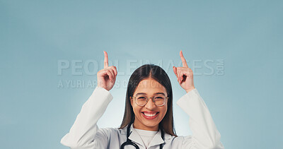 Buy stock photo Doctor, pointing and happy woman in studio, offer and presentation for healthcare service or advice. Blue background, medical expert and person with smile, portrait and health options with space