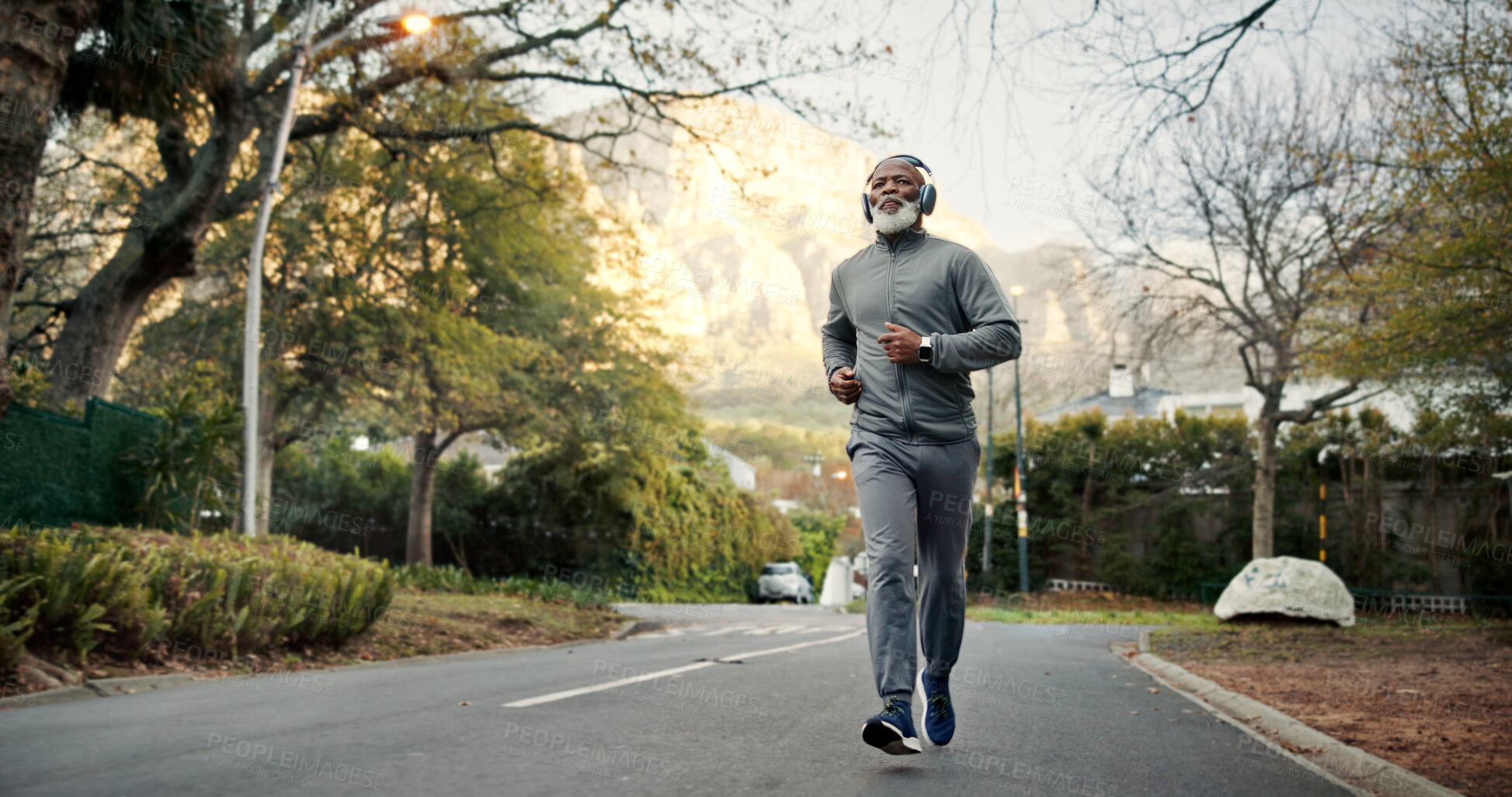 Buy stock photo Outdoor, man and running with headphones, fitness and listening to music for exercise and endurance. Streaming, song and black person with technology on road, mature runner and workout for wellness