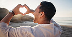 Smile, man and heart at beach for travel, love symbol and celebration for summer holiday. Happy, male person and hand gesture at seashore for kindness, romance icon and adventure for vacation getaway