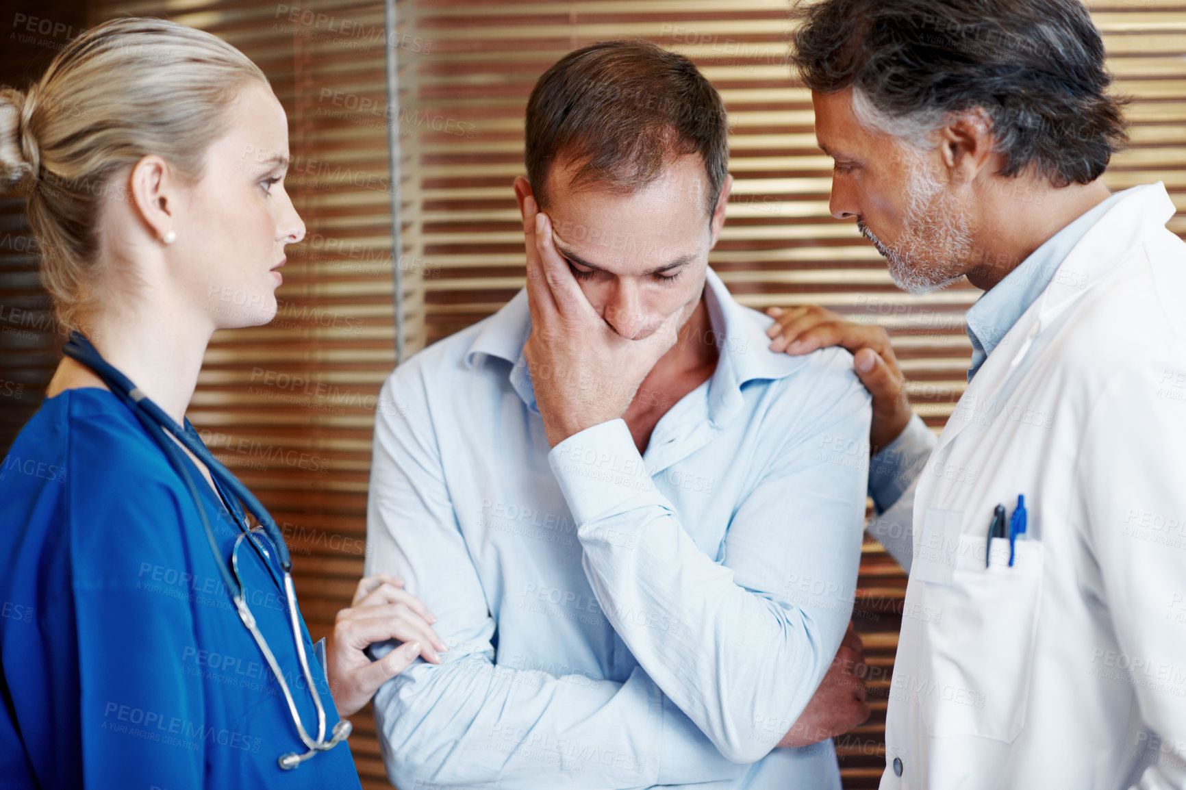 Buy stock photo Medical, team and comfort sad man in hospital with empathy, compassion and assurance for recovery. Doctor, nurse and worried person in clinic with stress, healthcare support or understanding emotions