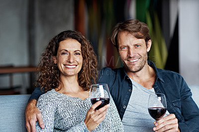 Buy stock photo Portrait of a smiling mature couple drinking wine while sitting on a sofa in their living room