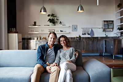 Buy stock photo Portrait of a smiling mature couple sitting on a sofa in their living room