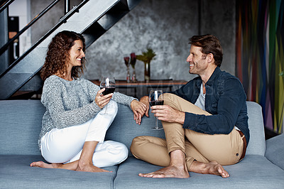 Buy stock photo Shot of an affectionate mature couple drinking wine while sitting on a sofa in their living room