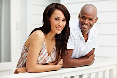 Buy stock photo Portrait of a young couple leaning on the railing of their balcony