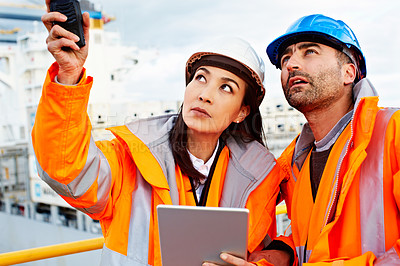 Buy stock photo Shot of two people talking over a digital tablet while standing on a large commercial dock