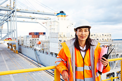 Buy stock photo Portrait of a woman in workwear holding a walkie talkie while standing on a large commercial dock