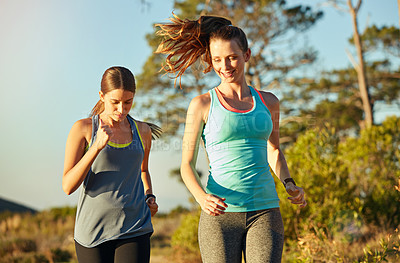 Buy stock photo Shot of two young woman out for a cross country run