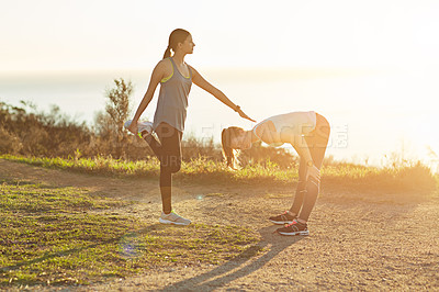 Buy stock photo Shot of two young friends stretching before a trail run