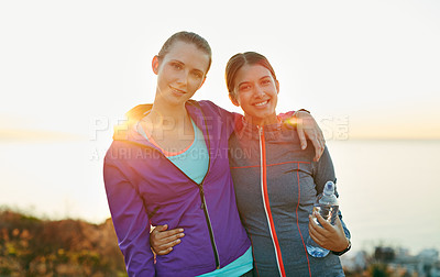 Buy stock photo Portrait of two young friends standing arm in arm after a run