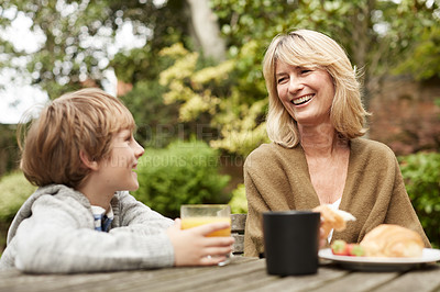Buy stock photo Shot of a grandmother and her grandson have lunch at a table in her yard