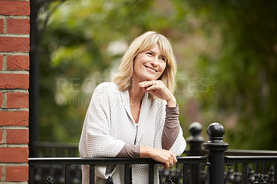 Buy stock photo Shot of a mature woman leaning against the railing of her front porch