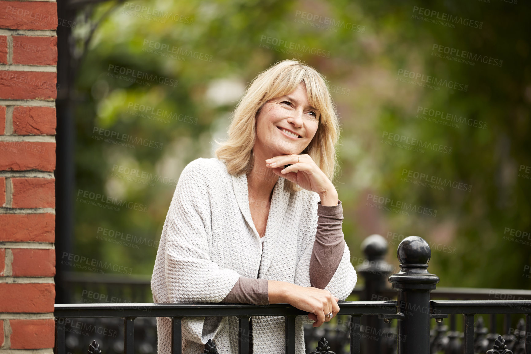 Buy stock photo Shot of a mature woman leaning against the railing of her front porch