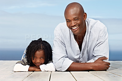 Buy stock photo Portrait of a father and his little son lying on a boardwalk outside