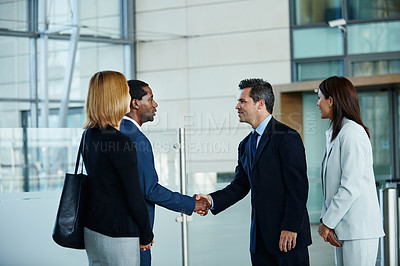 Buy stock photo Shot of businesspeople shaking hands together in the lobby of an office building
