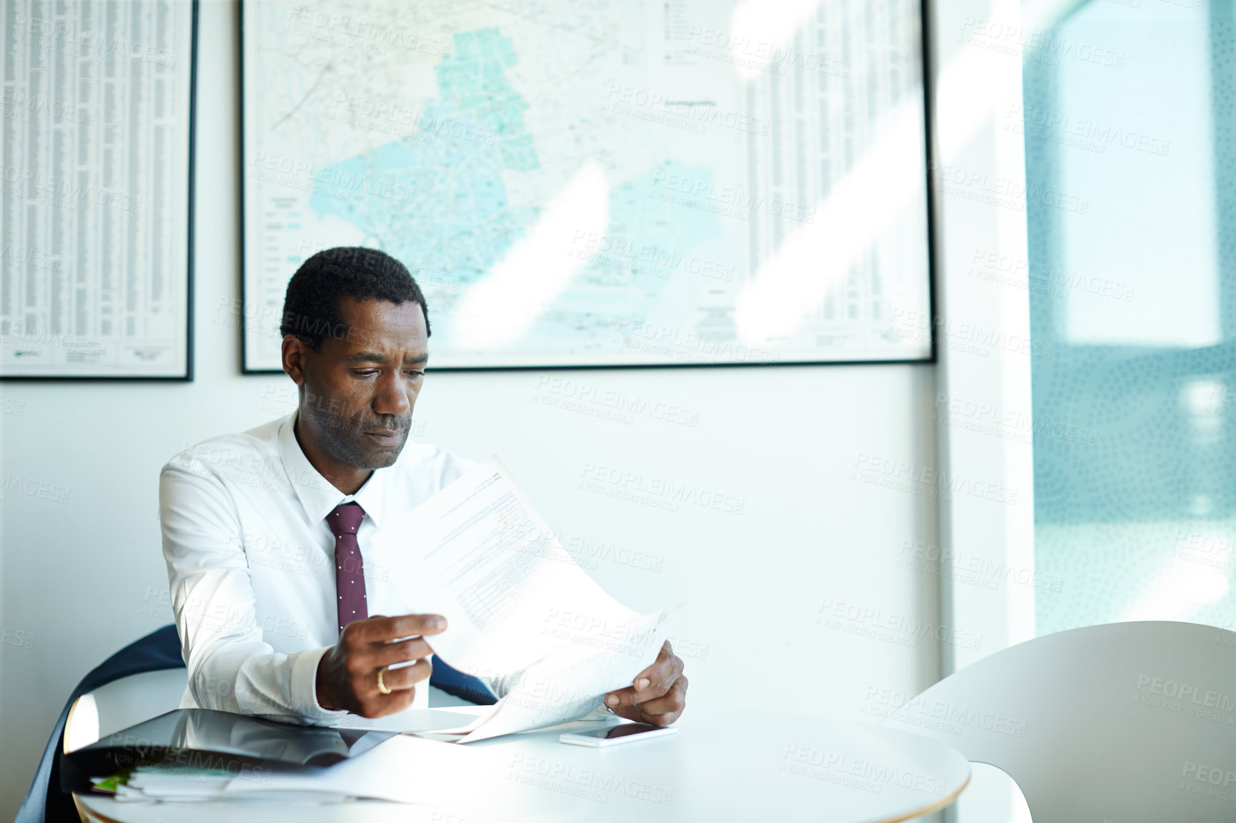 Buy stock photo Shot of a businessman sitting in an office going through paperwork