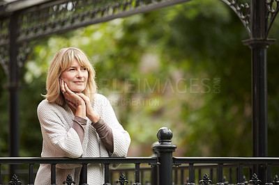 Buy stock photo Shot of a mature woman leaning against the railing of her front porch