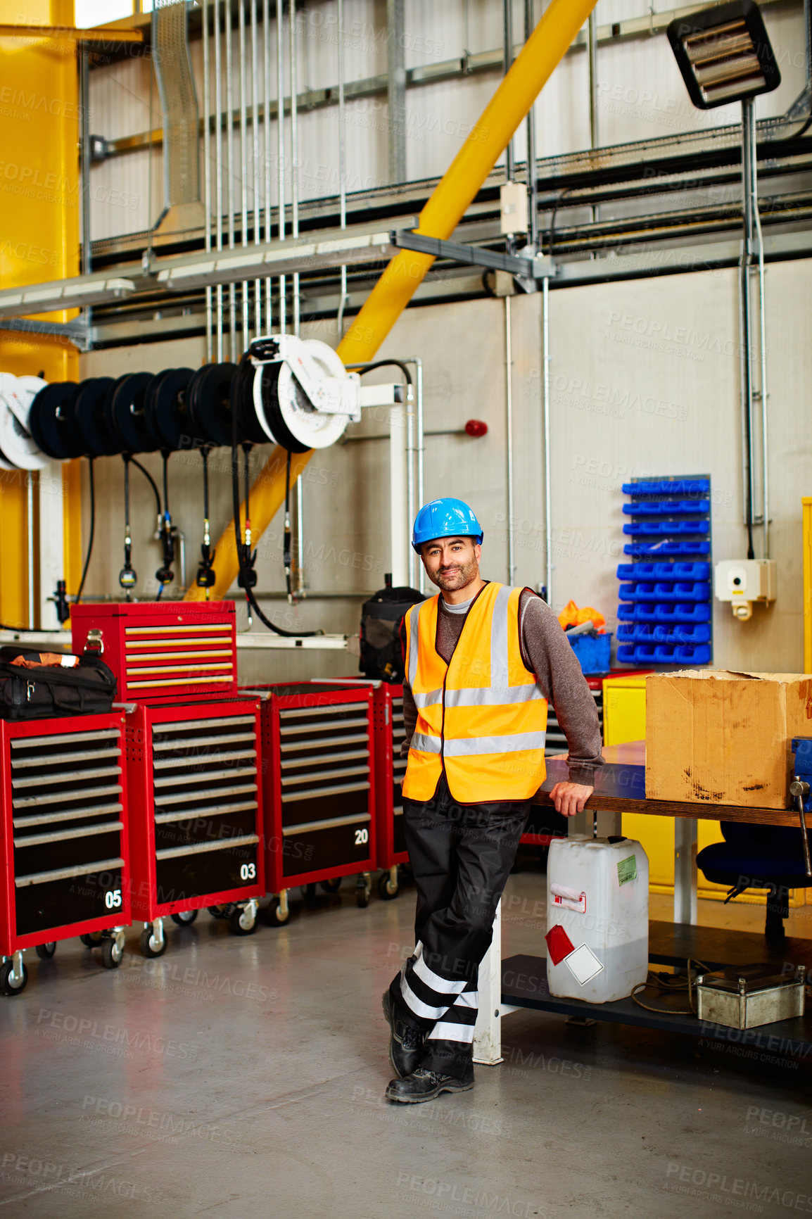 Buy stock photo Portrait of a man in workwear standing by toolboxes in a large industrial building