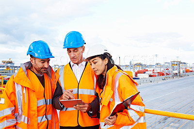 Buy stock photo Shot of three workers talking together over a digital tablet while standing on a commercial dock