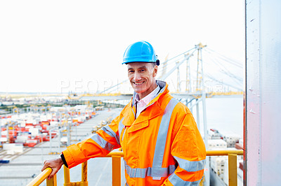 Buy stock photo Portrait of a man in workwear standing on a walkway looking out over at a large commercial dock