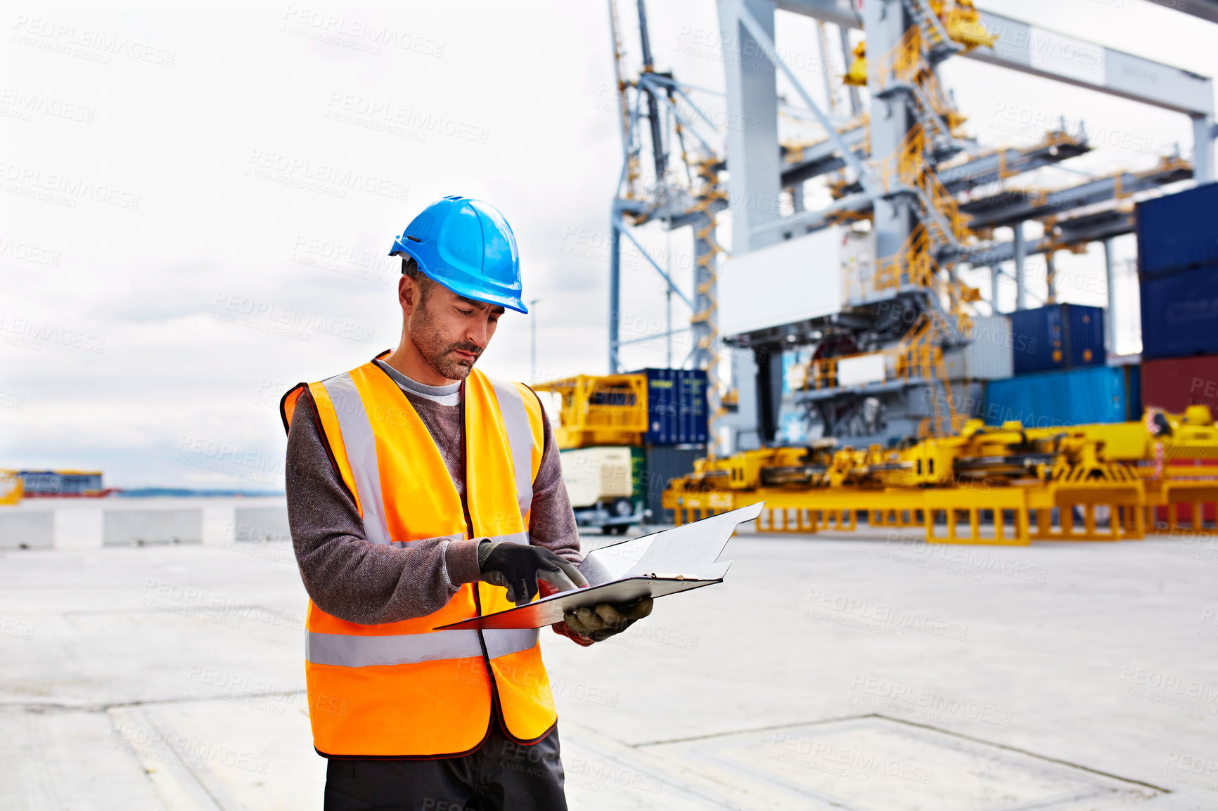 Buy stock photo Shot of man reading paperwork while standing on a large commercial dock