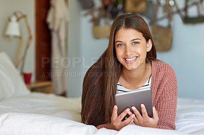 Buy stock photo Portrait of a young woman sitting on her bed using a digital tablet