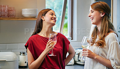 Buy stock photo Shot of two friends standing in a kitchen drinking wine together