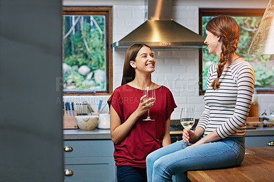 Buy stock photo Shot of two friends drinking wine together in the kitchen