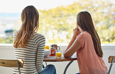 Buy stock photo Rearview shot of two friends eating breakfast together on a balcony