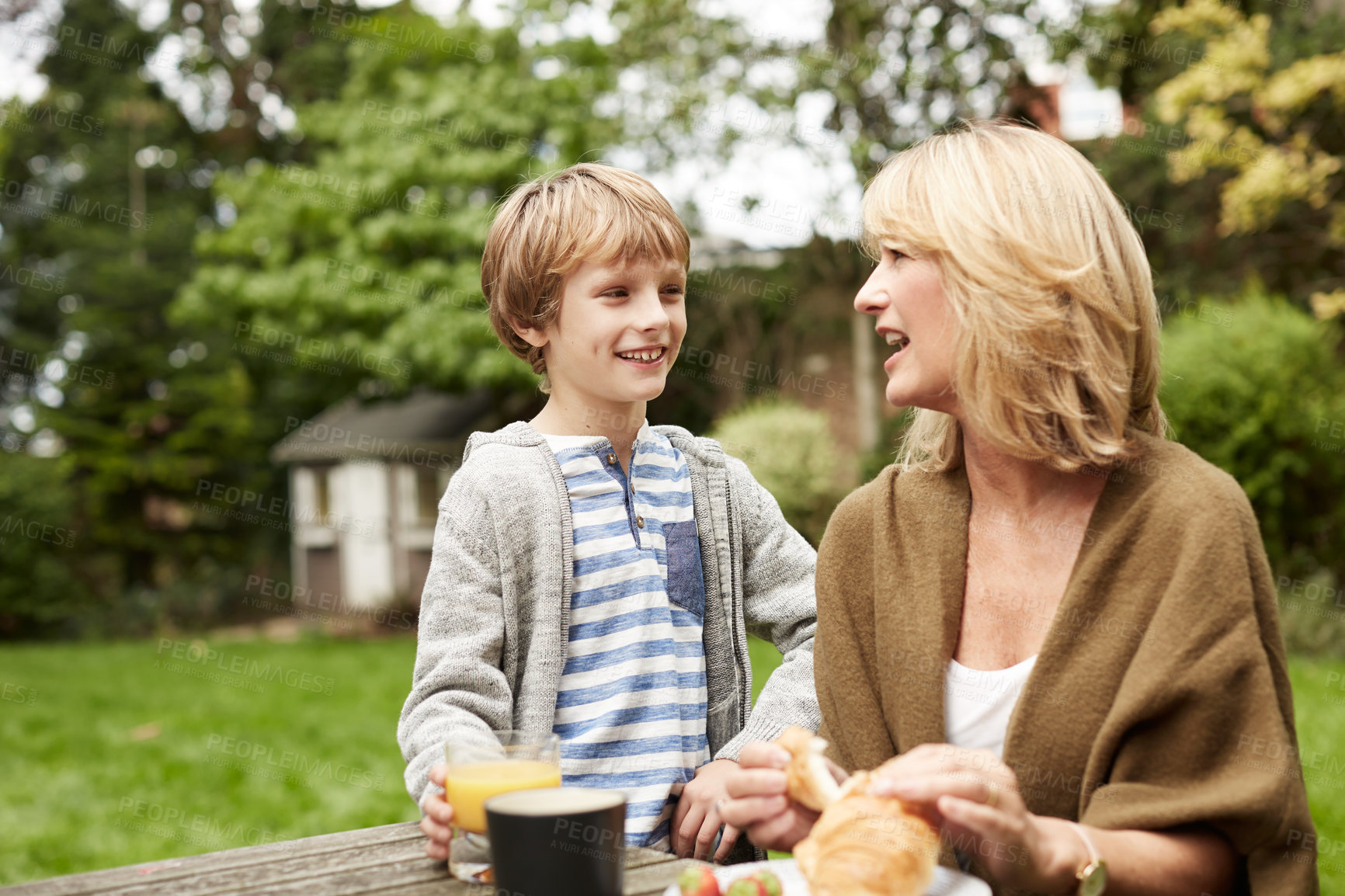 Buy stock photo Backyard, lunch and grandma with child, talking and smile with mature woman on weekend or connection. Outdoor, kid and happy person with food on break, family and bonding with grandson at house