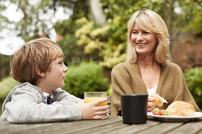 Buy stock photo Shot of a grandmother and her grandson have lunch at a table in her yard