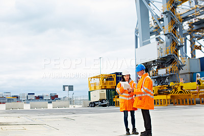 Buy stock photo Shot of two dock workers looking through paperwork while standing in a dockyard