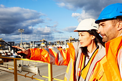 Buy stock photo Shot of a two workers standing on a large commercial dock