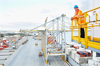 Buy stock photo Portrait of a man in workwear standing on a walkway looking  out over at a large commercial dock