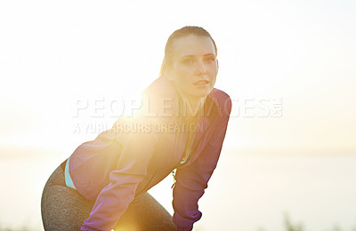 Buy stock photo Shot of a young woman taking a breather while out for a run