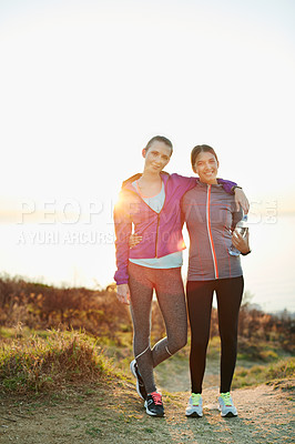 Buy stock photo Portrait of two young friends standing arm in arm after a run