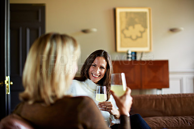 Buy stock photo Shot of two women sitting on a sofa drinking wine and talking