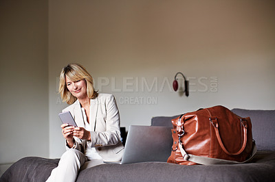 Buy stock photo Shot of a mature businesswoman sitting on a hotel bed using her cellphone