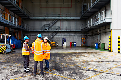 Buy stock photo Shot of three workers talking together while standing on a commercial dock