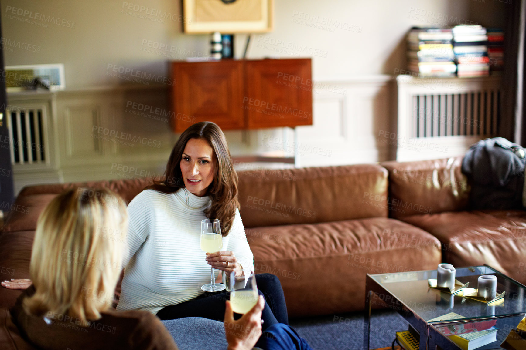 Buy stock photo Shot of a woman drinking wine while talking with her daughter on the living room sofa