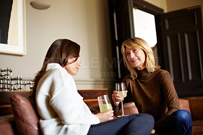 Buy stock photo Shot of a woman drinking wine while talking with her daughter on the living room sofa