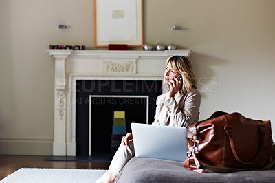 Buy stock photo Shot of a mature businesswoman using her laptop and cellphone while sitting on her hotel bed