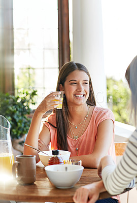 Buy stock photo Shot of two friends eating breakfast together on a balcony